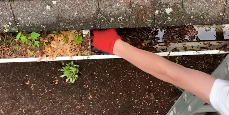 Technician hand-clearing gutter debris during a gutter cleaning job in Anderson, SC