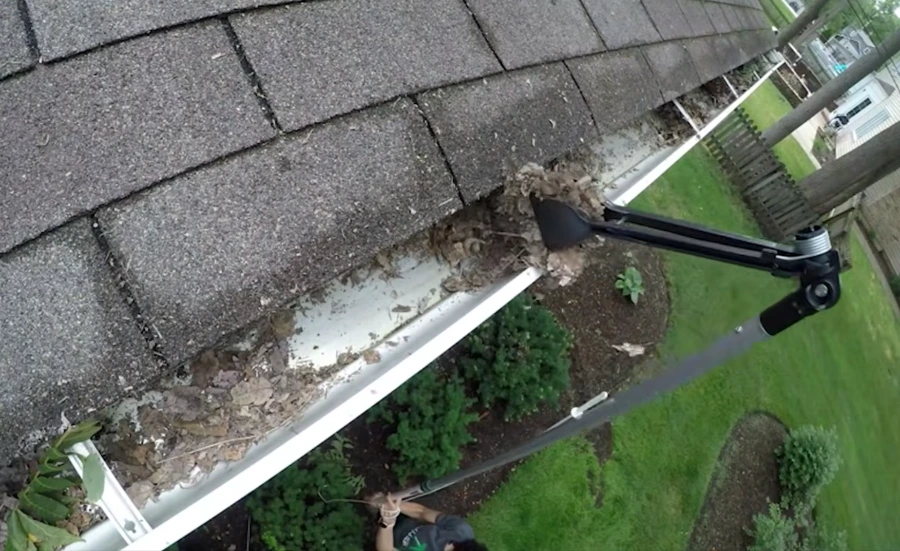 Technician hand-clearing gutter debris during a gutter cleaning job in Anderson, SC
